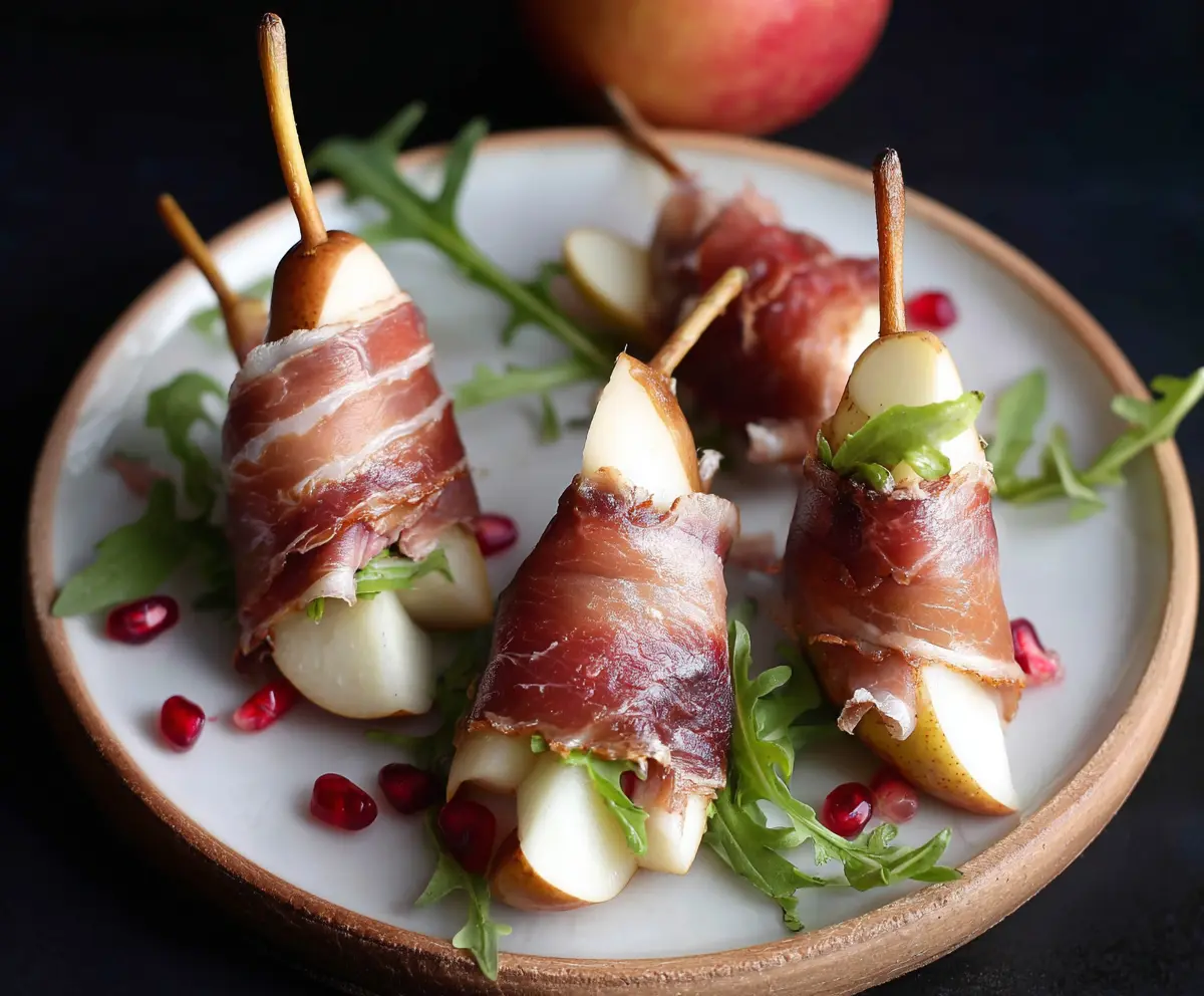 Delicious prosciutto wrapped pears garnished with herbs for elegant appetizer