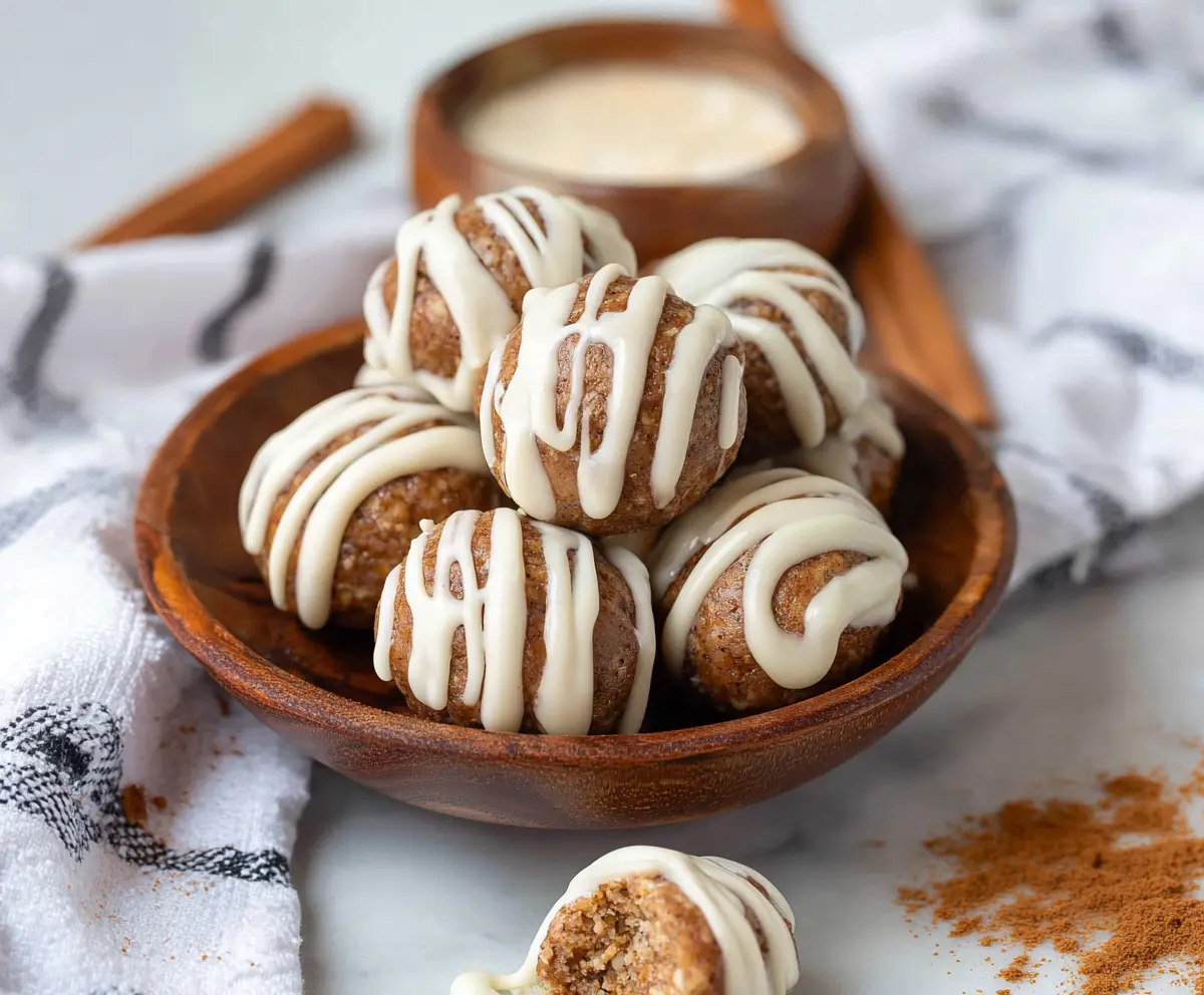 Delicious cinnamon roll protein bites topped with cinnamon and icing for a healthy snack.