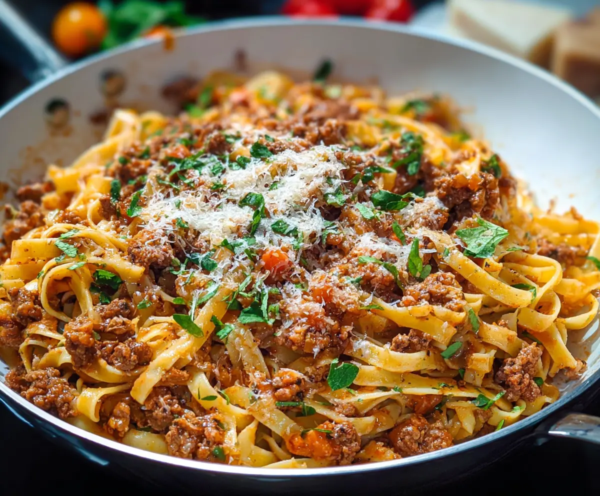 Delicious pork Bolognese pasta served on a white plate with fresh herbs
