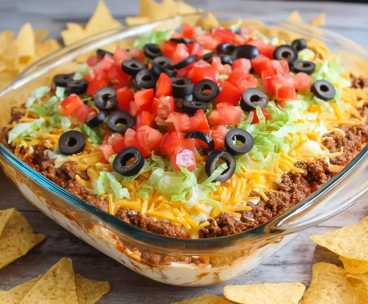 Delicious taco dip with seasoned ground beef, melted cheese, and fresh toppings perfect for parties.