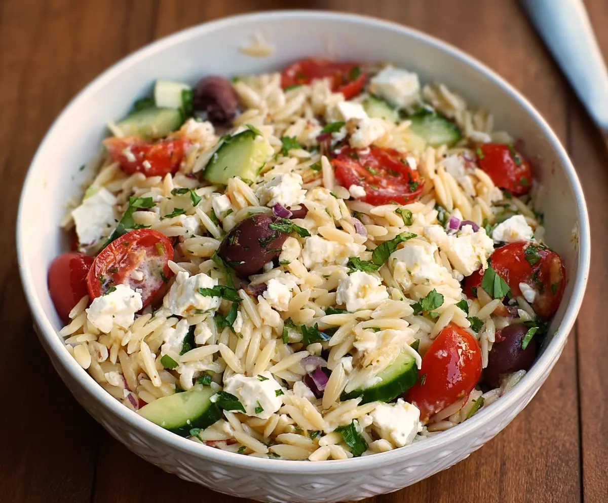 Fresh Feta Orzo Salad with cherry tomatoes and herbs on a rustic wooden table.