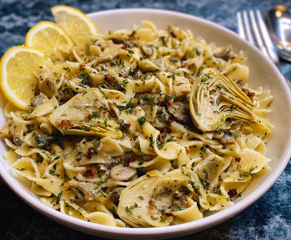 Delicious Lemon Artichoke Pasta dish with fresh herbs on a rustic plate.