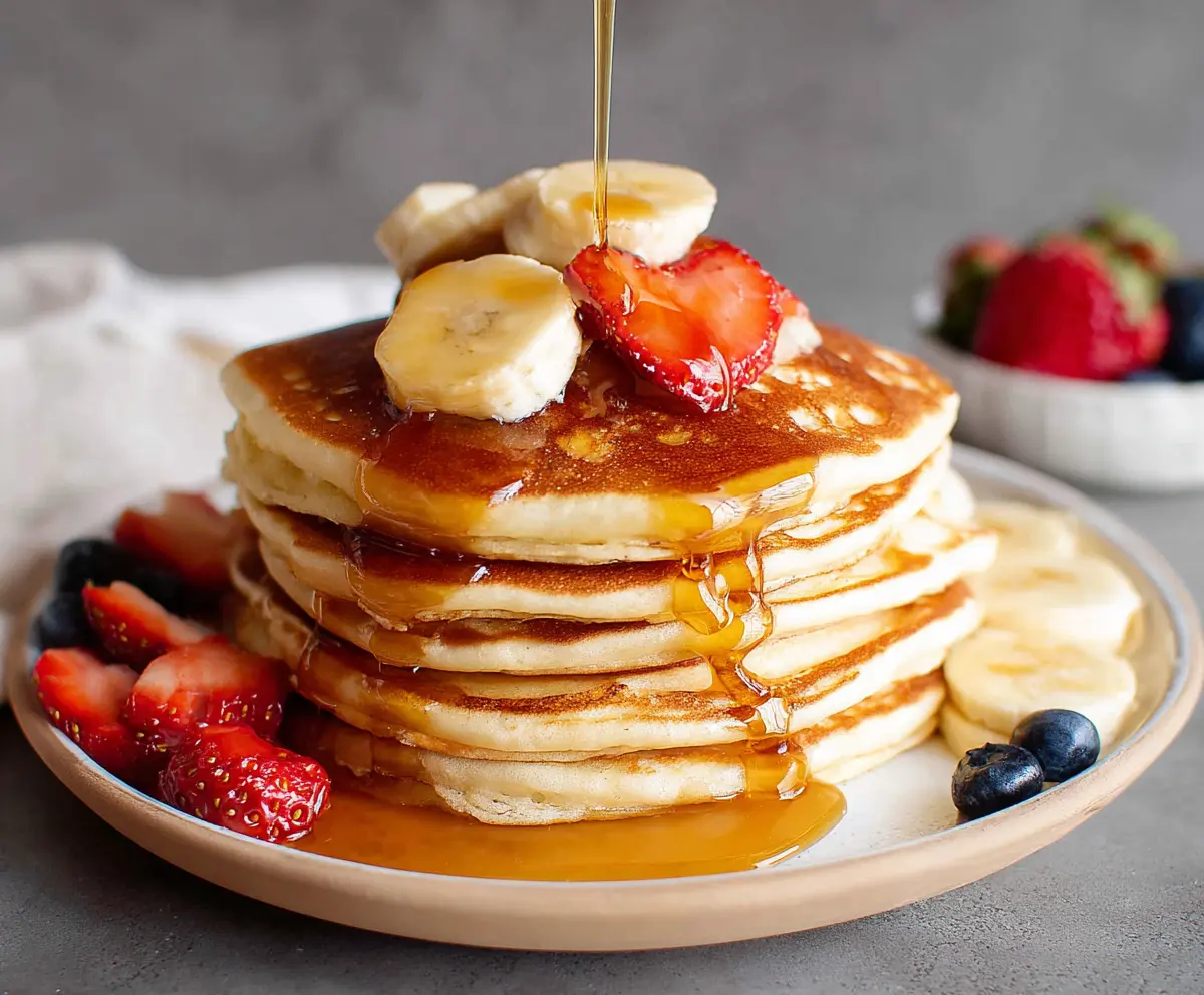 Delicious golden brown sourdough discard pancakes served on a white plate with fresh berries.