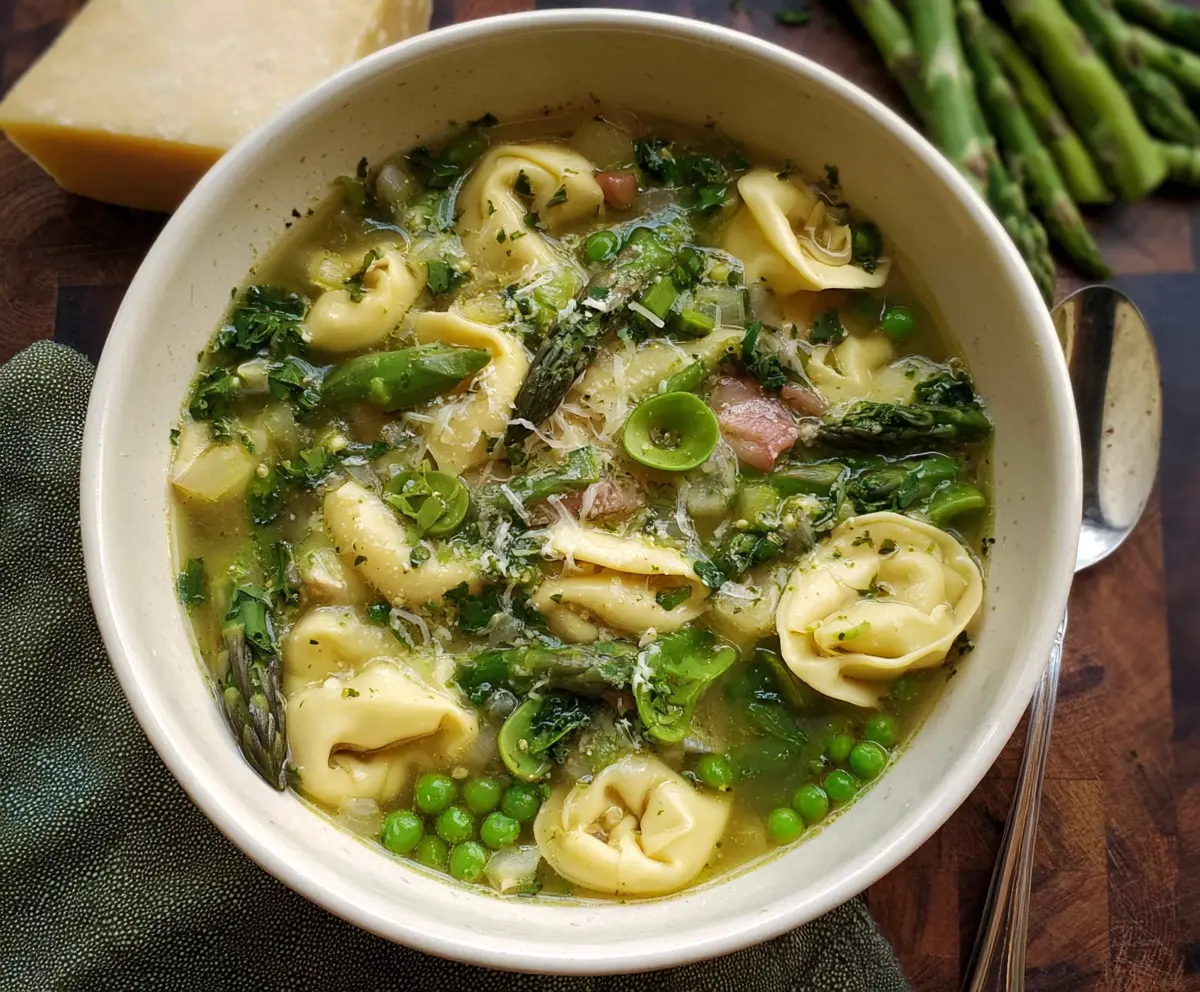 Delicious spring tortellini soup with fresh peas and asparagus in a bowl.
