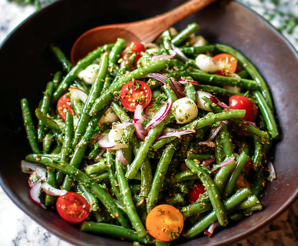 Fresh green bean salad with cherry tomatoes and herbs on a white plate, healthy summer dish.