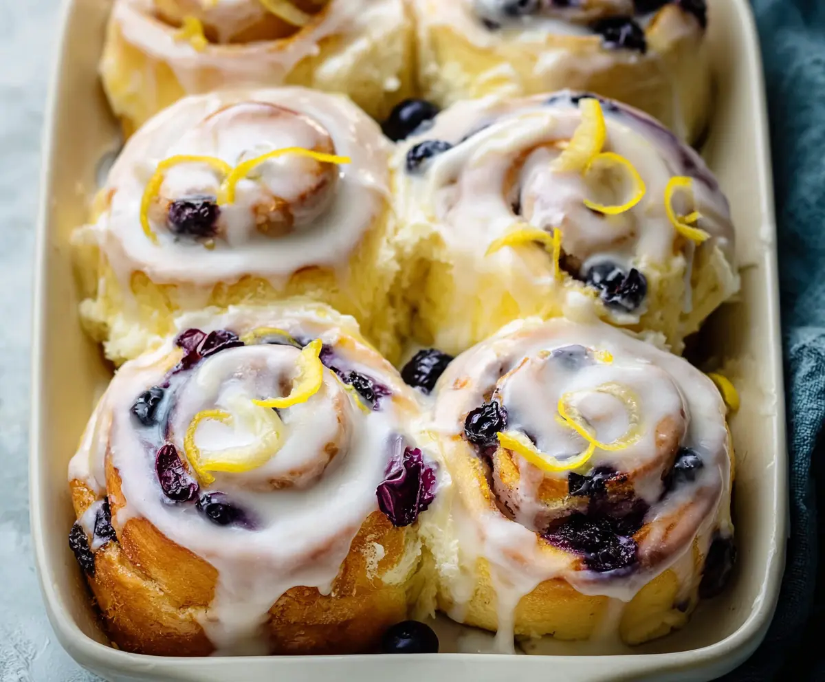 Delicious Lemon Blueberry Rolls with fresh blueberries and zesty lemon glaze on a wooden table.
